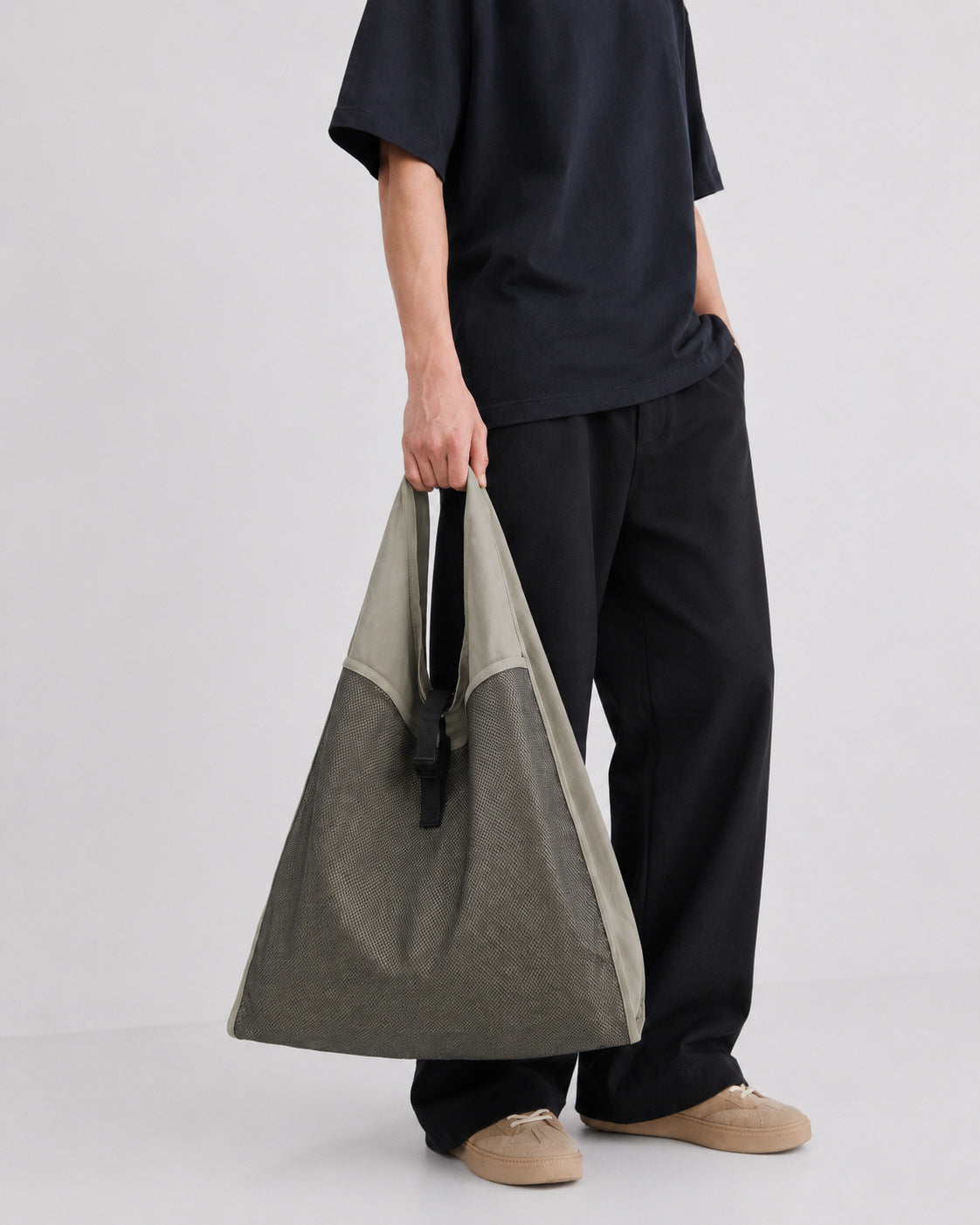 Oversized triangular mesh tote bag with matte olive-khaki fabric straps and trim, dark open-weave mesh body, matte black