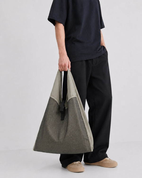Oversized triangular mesh tote bag with matte olive-khaki fabric straps and trim, dark open-weave mesh body, matte black