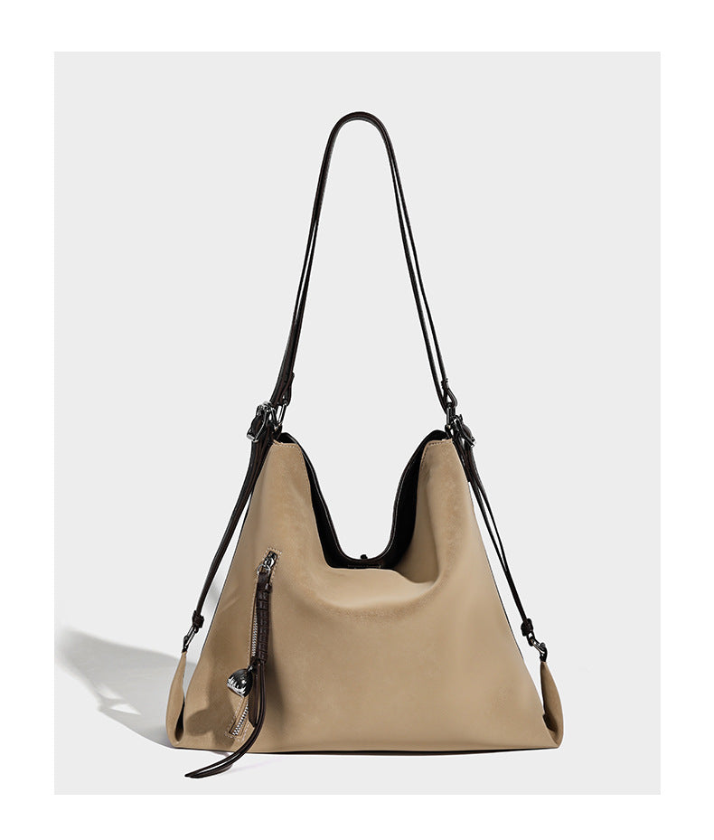 Slouchy hobo tote bag with matte leather-look finish, triangular silhouette, front zip pocket, and adjustable shoulder strap