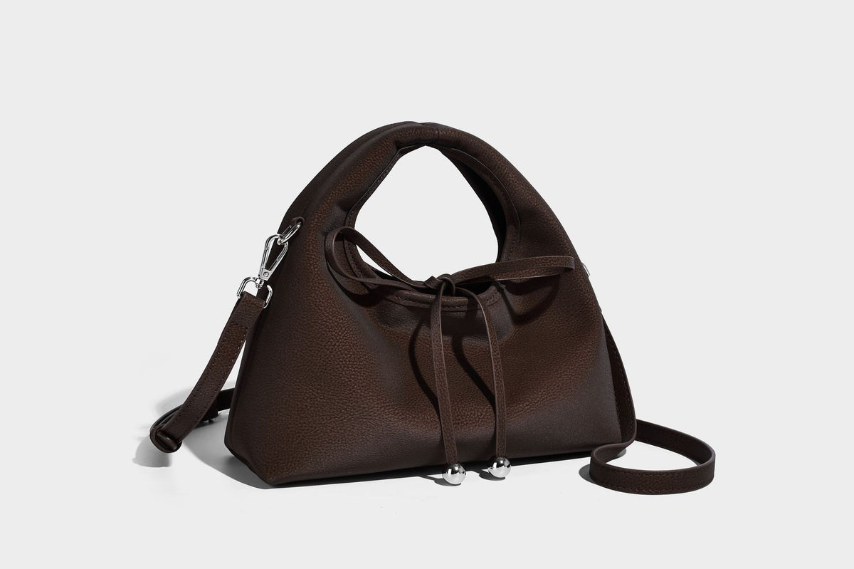 Pebbled matte trapezoid top-handle bag with drawstring bow closure, bead-tipped cords, silver-tone hardware, and detachable