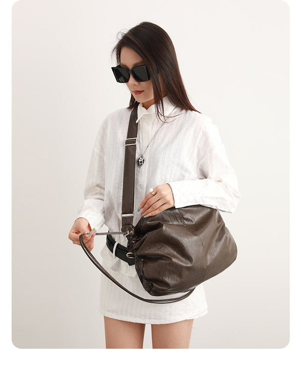 Oversized slouchy hobo shoulder bag with glossy crinkled leather-look finish, drawstring gathered sides, and silver-tone