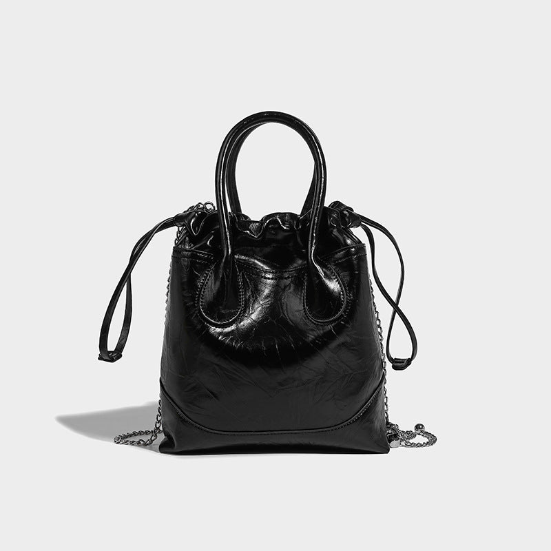 Glossy crinkled ruched drawstring bucket bag with rounded double top handles and detachable chain crossbody strap, front view
