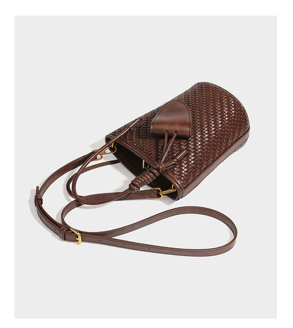 Structured woven-texture leather-look bucket bag in brown with knotted top handles, small front flap pouch, and adjustable