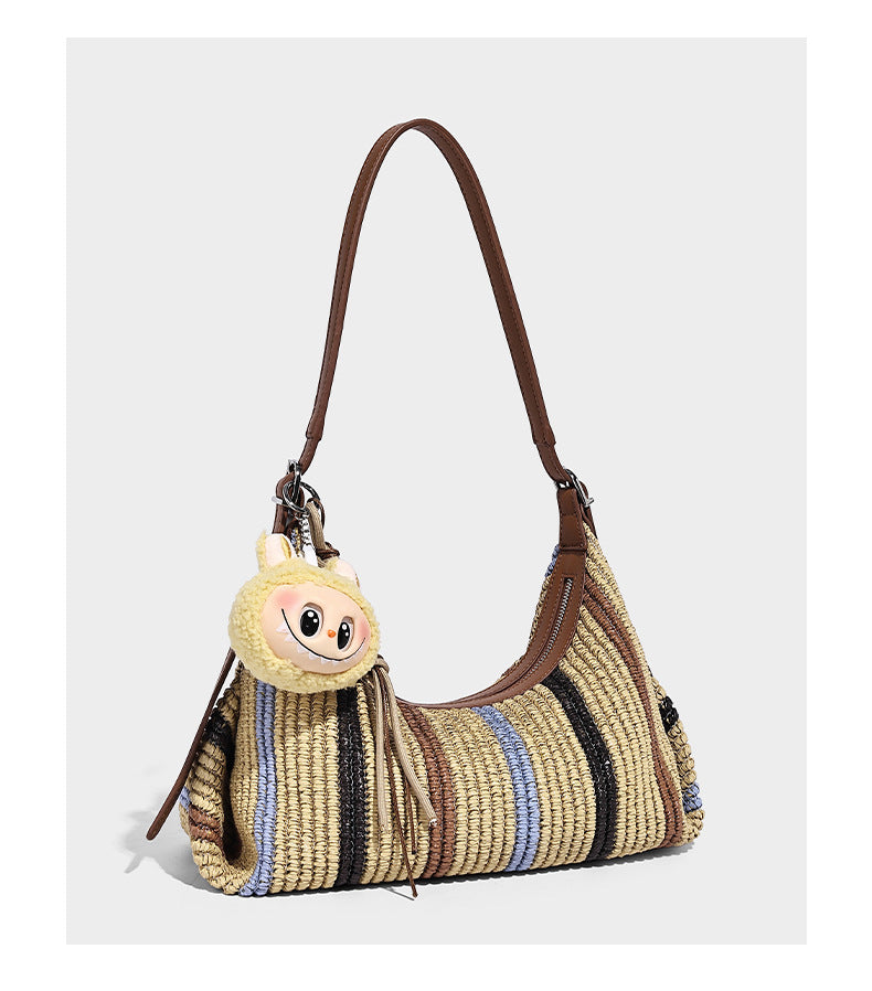 Slouchy woven straw hobo shoulder bag with beige, black, brown, and blue vertical stripes and brown leather-look trim, detail