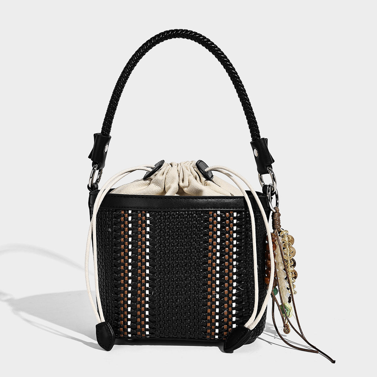 Small woven bucket bag with drawstring top, braided handle, detachable crossbody strap, and silver-tone ring hardware, detail