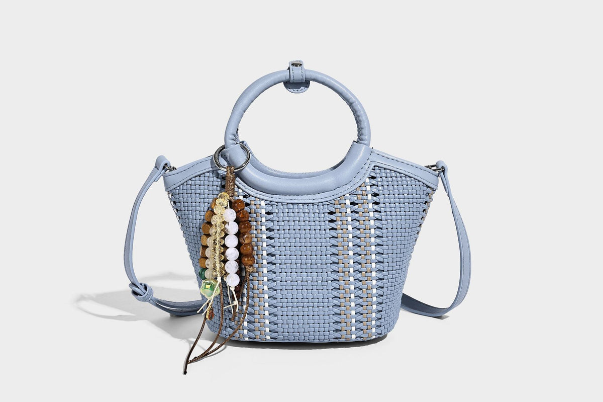 Kleine strukturierte Beuteltasche aus geflochtenem Material mit rundem Tragegriff in Lederoptik, silberfarbenen Beschlägen und perlenbesetztem Quastenanhänger, Detail