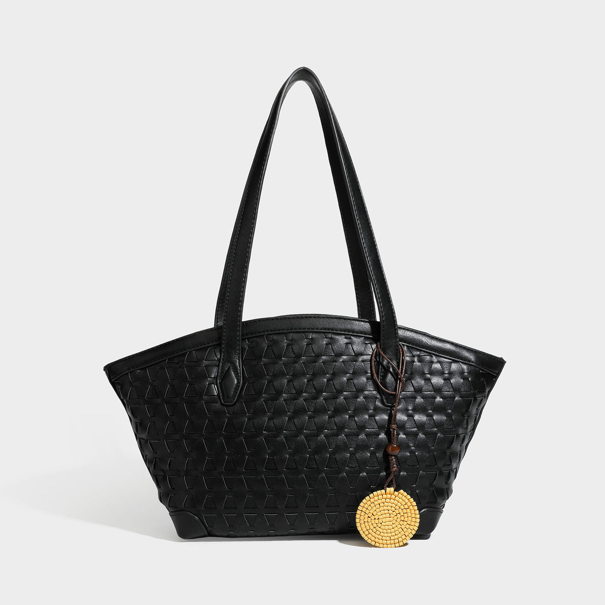 Large leather-look tote bag with geometric woven emboss, double shoulder straps, and round woven cord charm in brown, detail