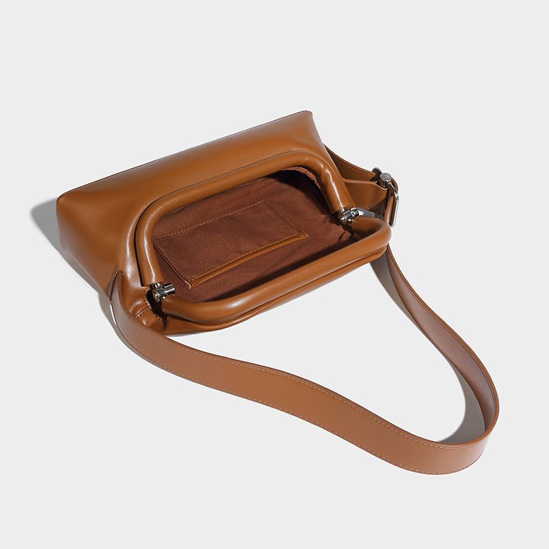 Compact structured baguette shoulder bag with smooth leather-look finish, zip top, and adjustable silver-buckle strap, detail