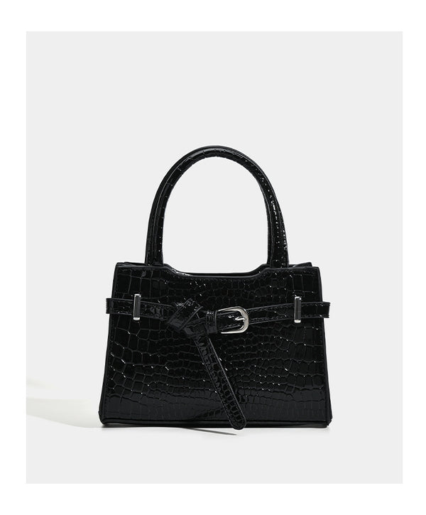 Small structured trapezoid mini top-handle bag with front belt-knot buckle detail and glossy leather-look finish, detail view