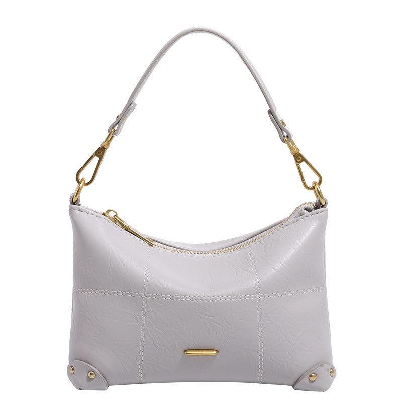 Small soft-structured shoulder bag with curved zip closure, stitched panel detailing, and gold-tone hardware, detail view 5