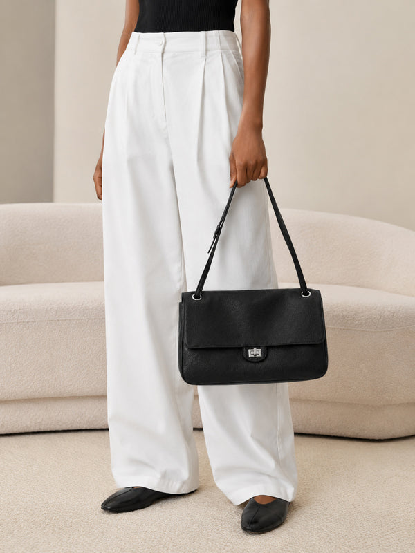 Structured black flap shoulder bag with pebbled texture, silver-tone turn-lock closure, and adjustable single shoulder strap