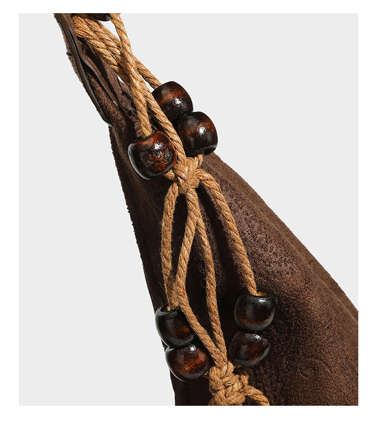 Slouchy boho hobo shoulder bag in embossed brown suede-look finish with beaded strap, cord tassels, and brass-tone leaf