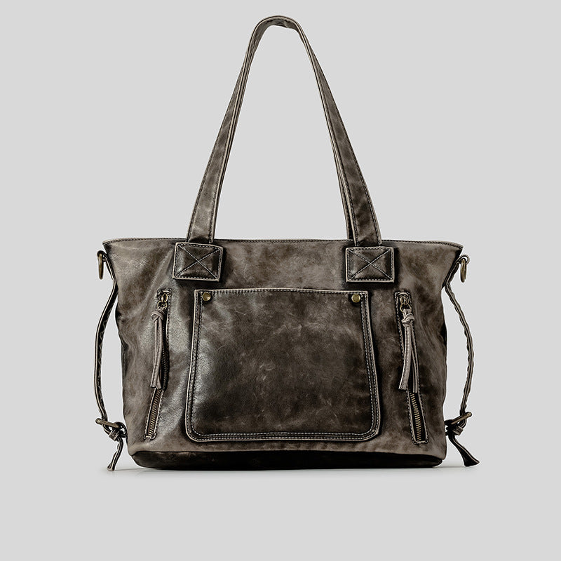 Distressed leather-look convertible tote bag with dual top handles, front zip and patch pockets, and adjustable shoulder