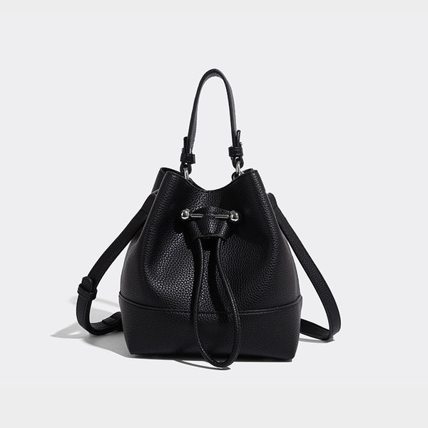 Small two-tone pebbled drawstring bucket bag with tan contrast base, metal toggle hardware, short top handle, and detachable