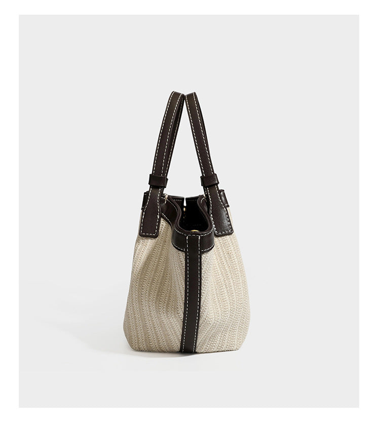 Cremefarbene geflochtene Tote-Bag mit dunkelbraunen Besätzen in Lederoptik, kontrastierenden weißen Nähten, zwei oberen Henkeln und abnehmbarem Schulter