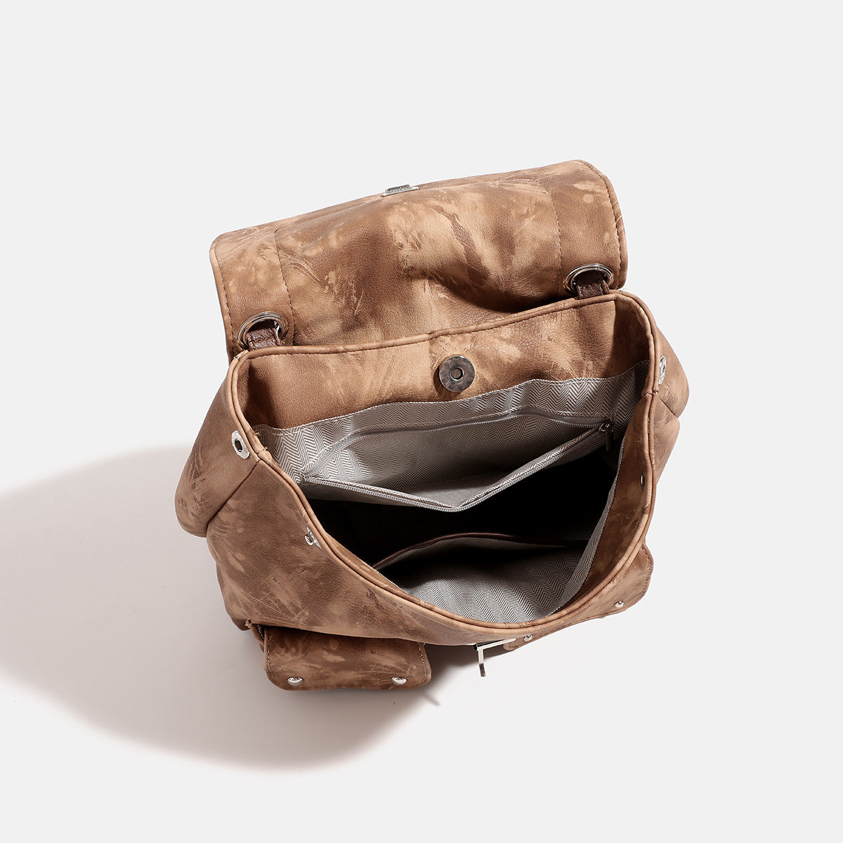Compact distressed leather-look tan-brown backpack handbag with flap-and-buckle closure, two front patch pockets, top handle