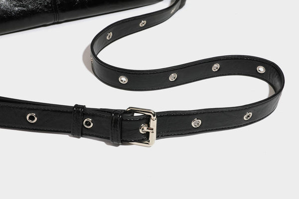 Black glossy leather-look slouchy shoulder bag with silver stud and eyelet hardware, top zip closure, front zip pocket, and