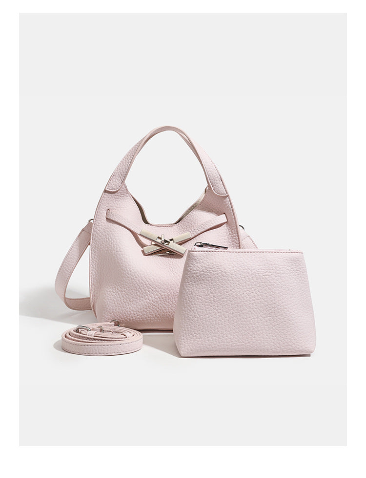 Compact pebbled leather-look shoulder bag with crossed silver-toned metal front closure, short top handle, and long, detail