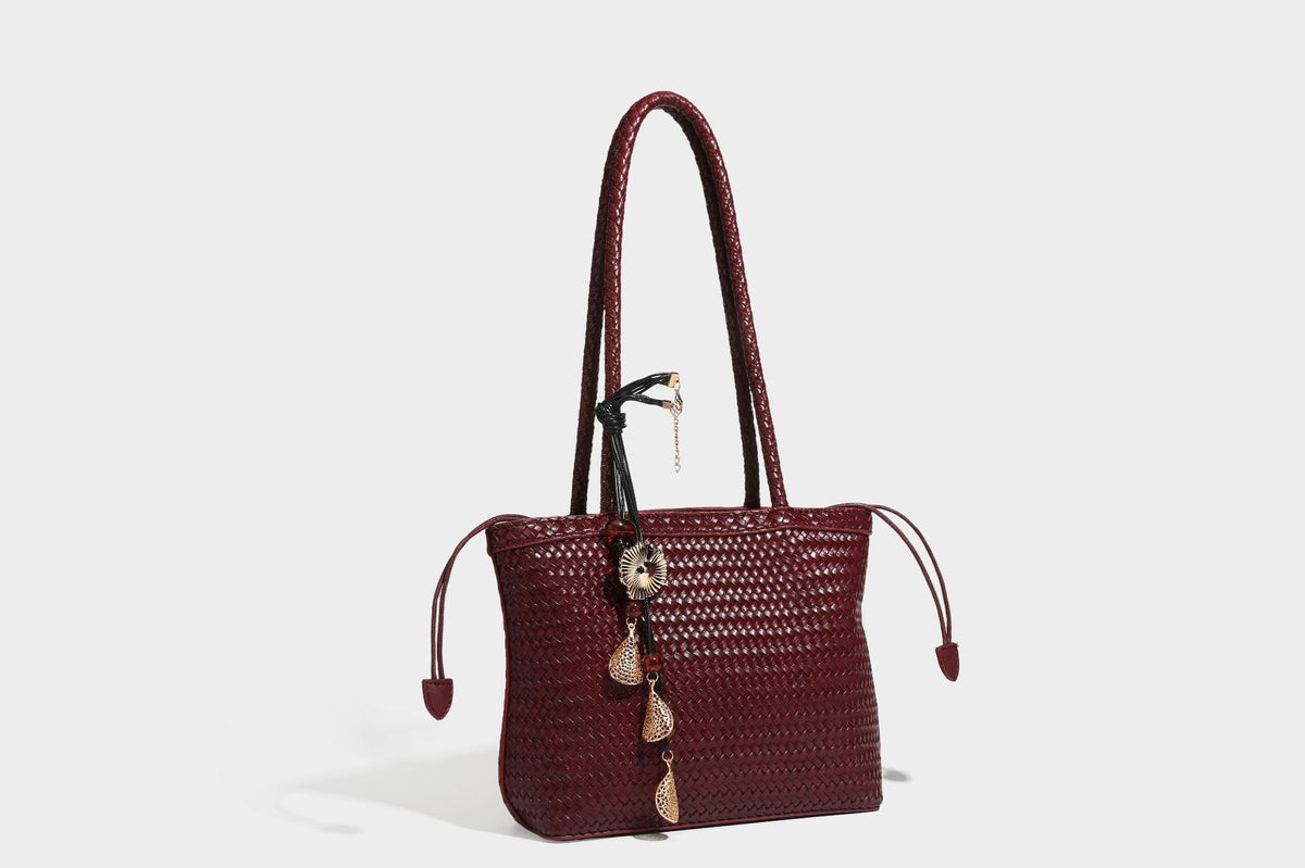 Structured woven leather-look tote bag in dark brown with long shoulder straps, side drawstring ties, and gold filigree