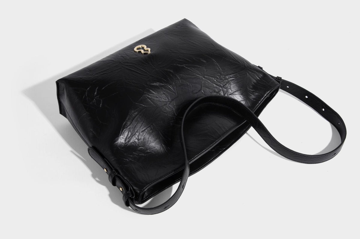 Large slouchy hobo shoulder bag in glossy crinkle leather-look finish with gold-tone emblem hardware and adjustable strap