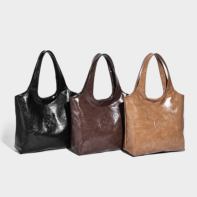 Glossy oil-wax leather-look open-top tote shoulder bag with embossed circular logo and long double straps, detail view 2