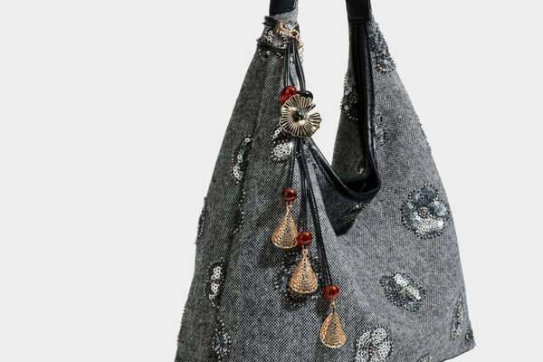 Lässig fallende, trapezförmige Schulter-Tote in Anthrazitgrau mit floralen Paillettenmotiven in Silber, Riemen in Lederoptik und herabhängendem Perlenbesatz