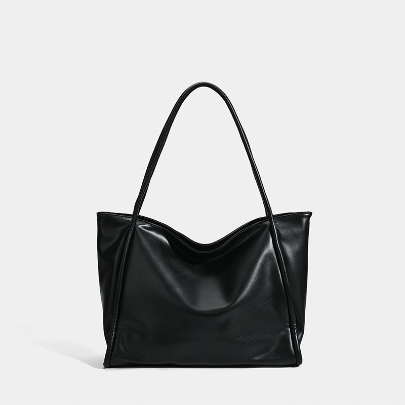 Large black glossy leather-look tote bag with dual shoulder straps and gently curved top edge, front view