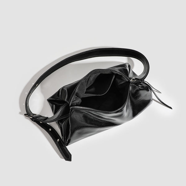 Black glossy leather-look slouchy shoulder bag with gathered top, zip tassel closure, and long adjustable silver-buckle