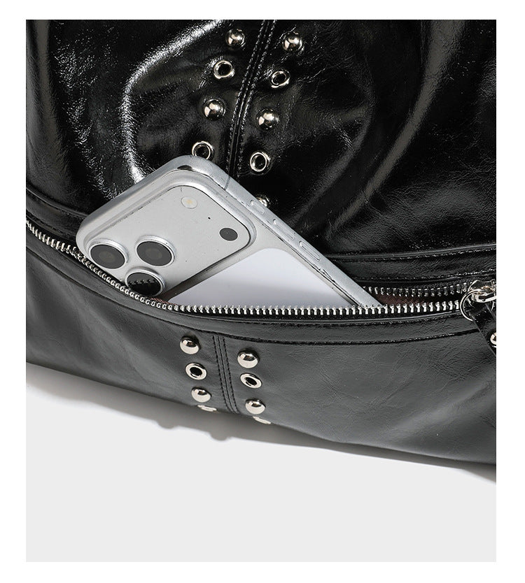 Black glossy leather-look slouchy shoulder bag with silver stud and eyelet hardware, top zip closure, front zip pocket, and