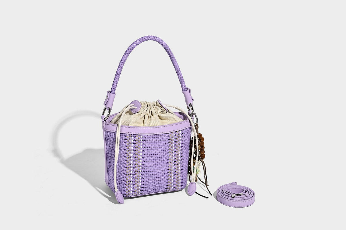 Small woven bucket bag with drawstring top, braided handle, detachable crossbody strap, and silver-tone ring hardware, detail
