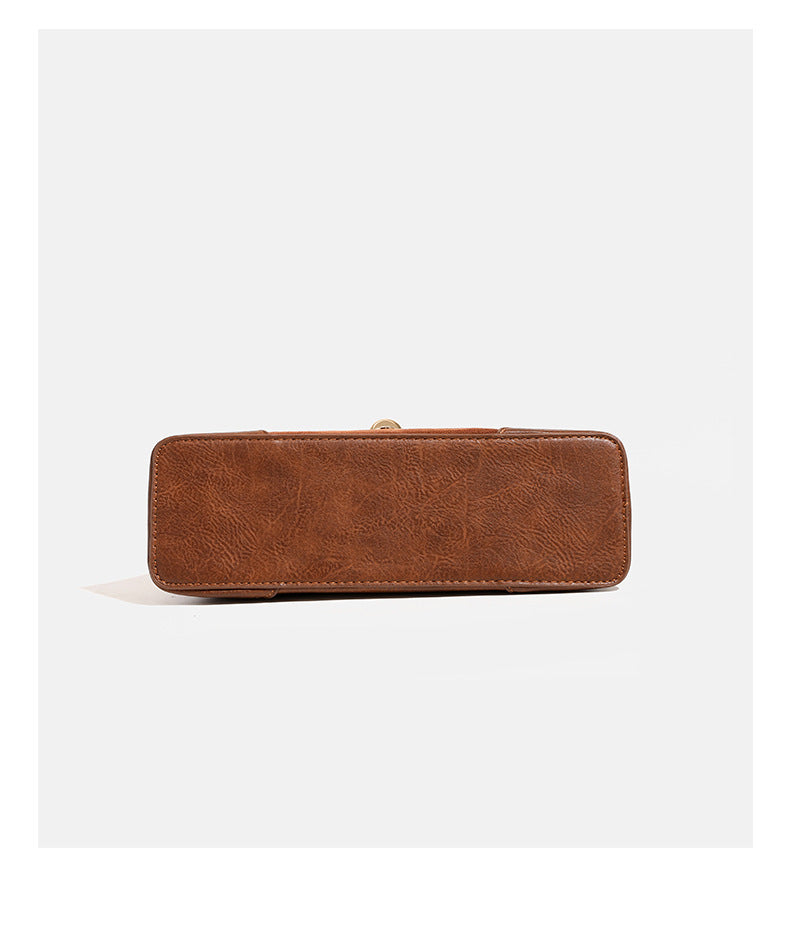 Structured trapezoid shoulder bag with pale textured flap, gold-tone triangular turn-lock closure, and long knotted cord