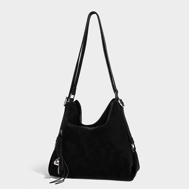Slouchy hobo tote bag with matte leather-look finish, triangular silhouette, front zip pocket, and adjustable shoulder strap