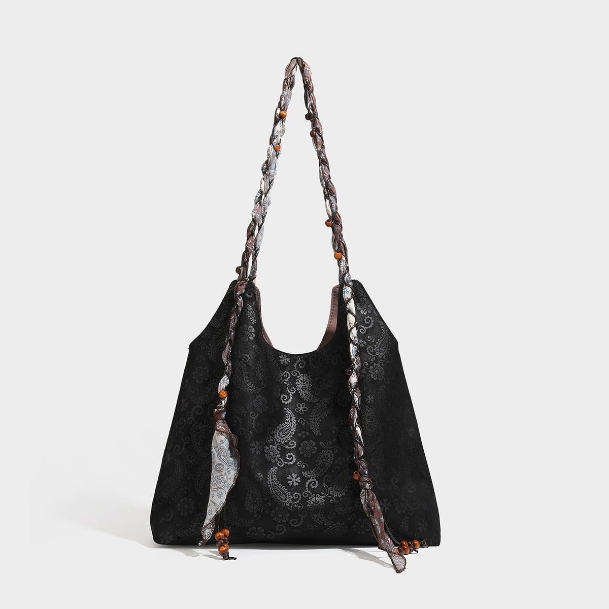 Slouchy paisley-embossed suede-look shoulder tote bag with braided patterned fabric straps and wood bead accents, detail view