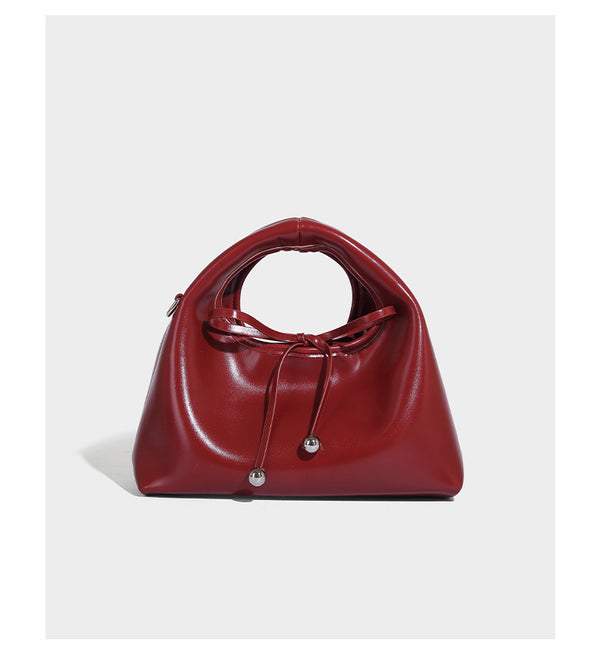 Kleine kuppelförmige Henkeltasche in glänzender Lederoptik mit Kordelzugverschluss, weißem Spitzen-Schleifenanhänger und silberfarbenen Metallbeschlägen