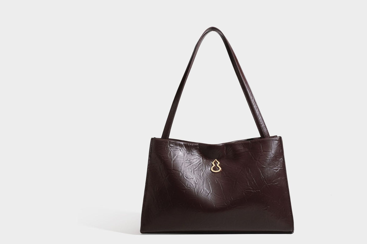 Strukturierte rechteckige Tote-Schultertasche aus glänzender, geknitterter Lederoptik mit langen Doppelträgern und Emblem in Goldoptik