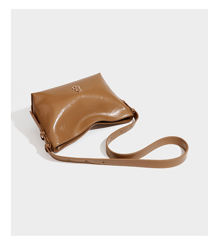 Lässige Hobo-Schultertasche mit offenem oberen Abschluss in glänzender karamellfarbener Lederoptik mit goldfarbenen Logo-Beschlägen und langem, verstellbarem