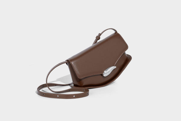 Small structured saddle bag with glossy leather-look finish, angular flap front, silver-tone metal clasp, and slim