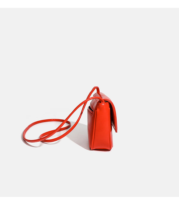Compact rounded rectangular flap crossbody bag with glossy leather-look finish and long shoulder strap, detail view 12