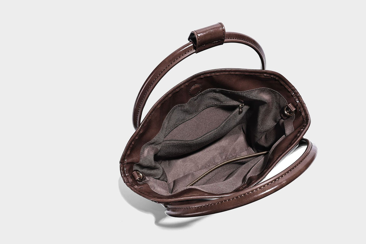 Glossy leather-look structured tote bag with rounded top handles, detachable shoulder strap, embossed front emblem, and side