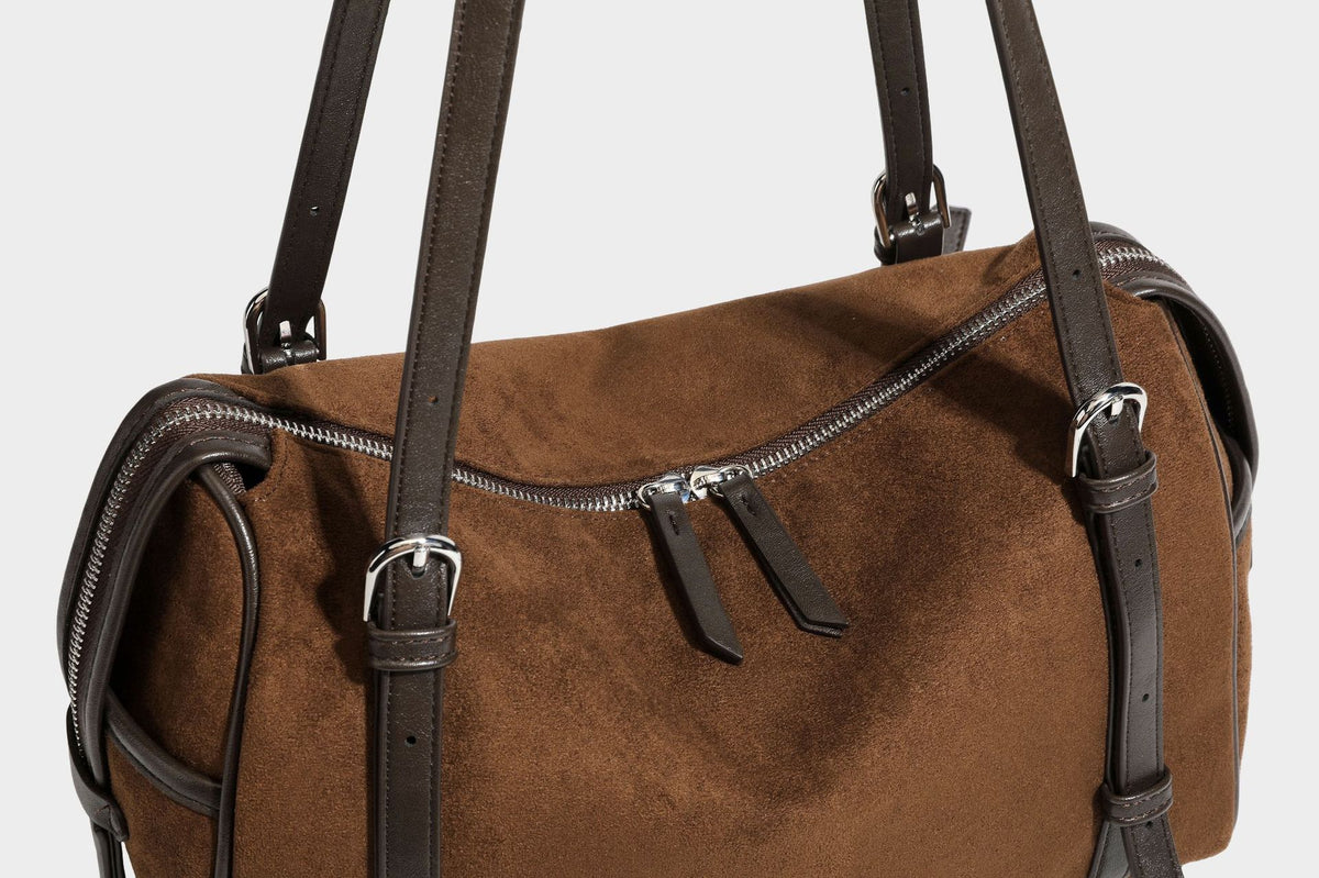 Large brown suede-finish barrel shoulder bag with dark leather-look trim, silver-tone zippers, dual top handles, and long