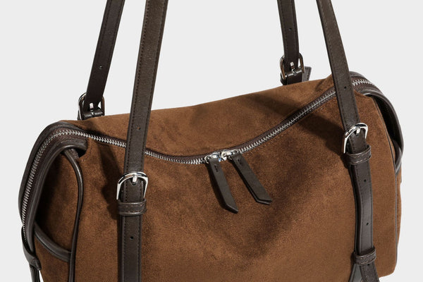 Large brown suede-finish barrel shoulder bag with dark leather-look trim, silver-tone zippers, dual top handles, and long
