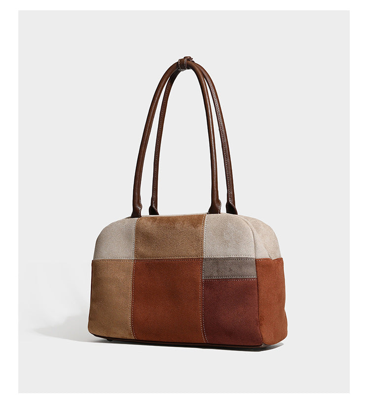 Boxy patchwork suede-look shoulder tote in tan, beige, rust, and brown panels with double brown straps and hanging doll