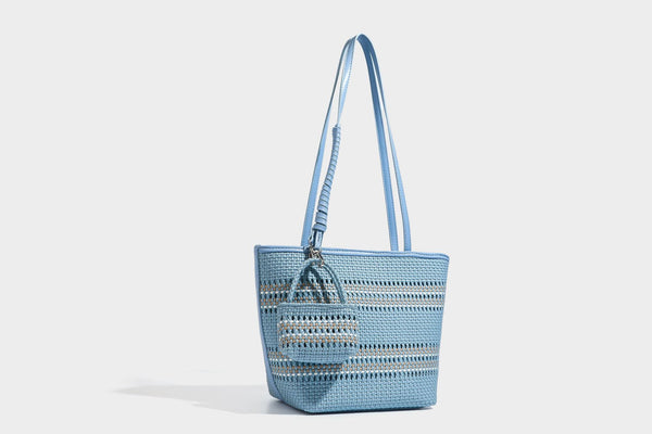 Large structured woven tote bag with striped basket-weave finish, long shoulder straps, and detachable mini pouch charm