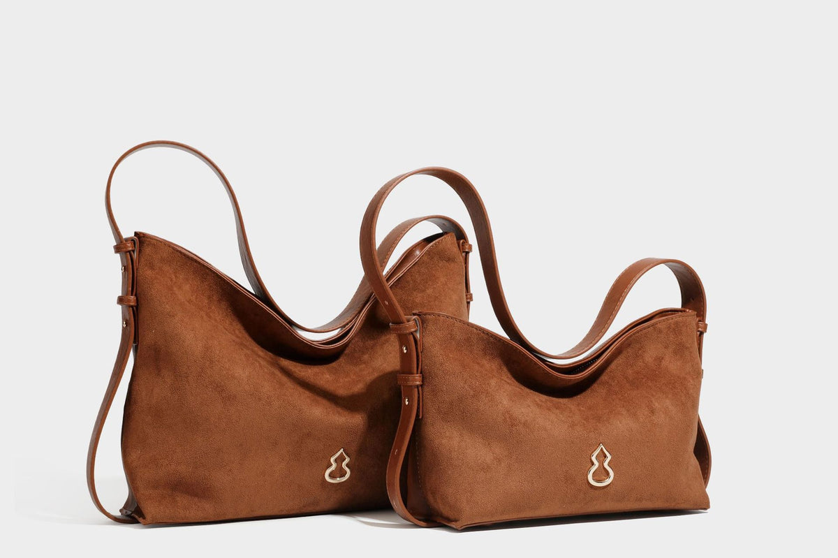 Slouchy suede-finish brown shoulder bag with long single strap and small gold-tone logo emblem on front, detail view 31