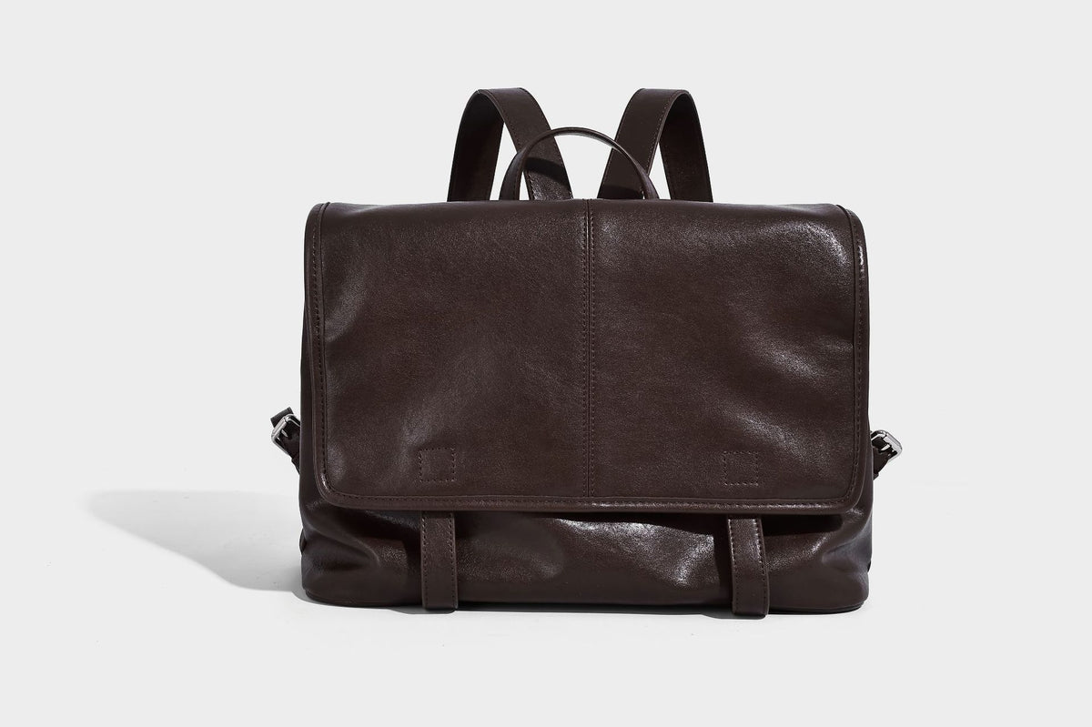 Structured tan leather-look flap backpack handbag with top handle, silver buckle hardware, and fold-over front closure