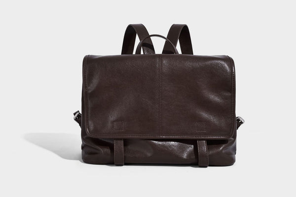Structured tan leather-look flap backpack handbag with top handle, silver buckle hardware, and fold-over front closure