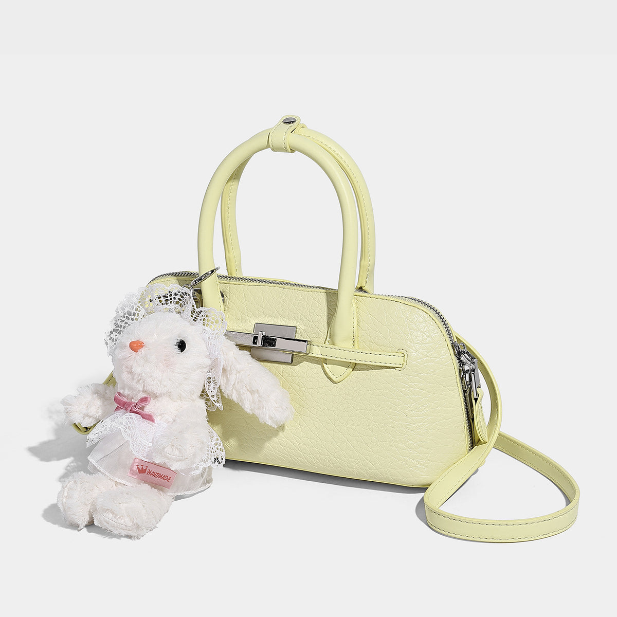 Small structured shell-silhouette top-handle bag with pebbled leather-look finish, silver-tone turn-lock hardware, and