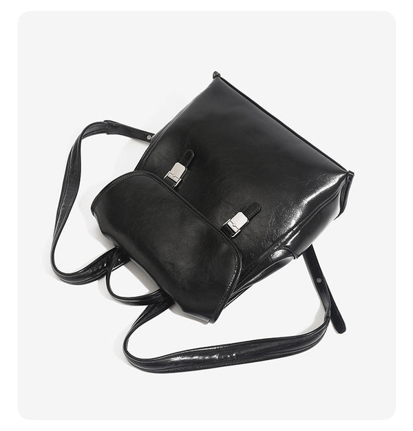 Structured glossy leather-look flap backpack handbag with dual buckle closures, top handle, and silver-tone hardware, detail