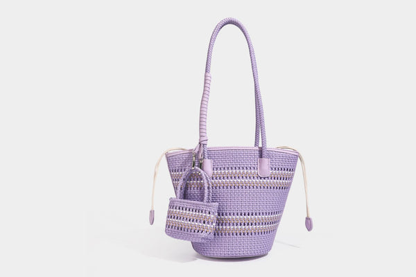 Light blue open-weave woven bucket tote bag with long braided shoulder straps, drawstring side ties, and attached mini pouch