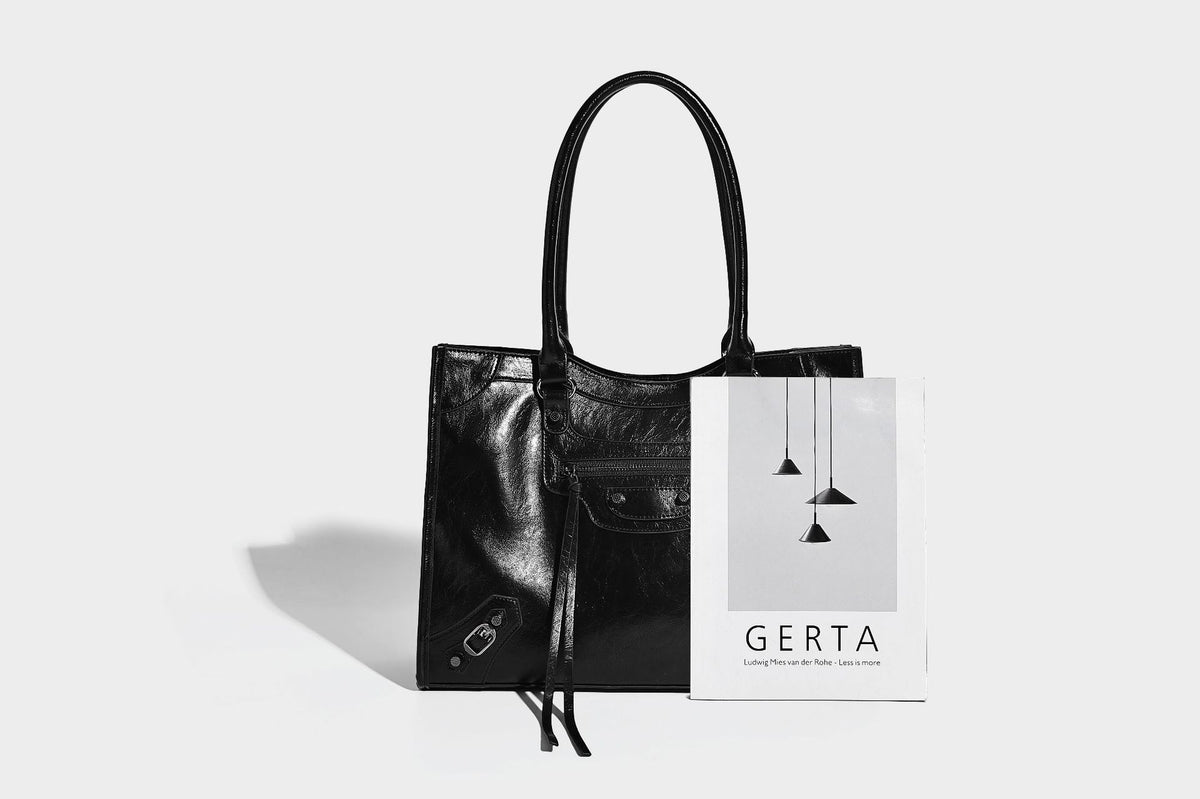 Large structured leather-look tote bag with front zip pocket, moto hardware accents, and long double shoulder straps, detail